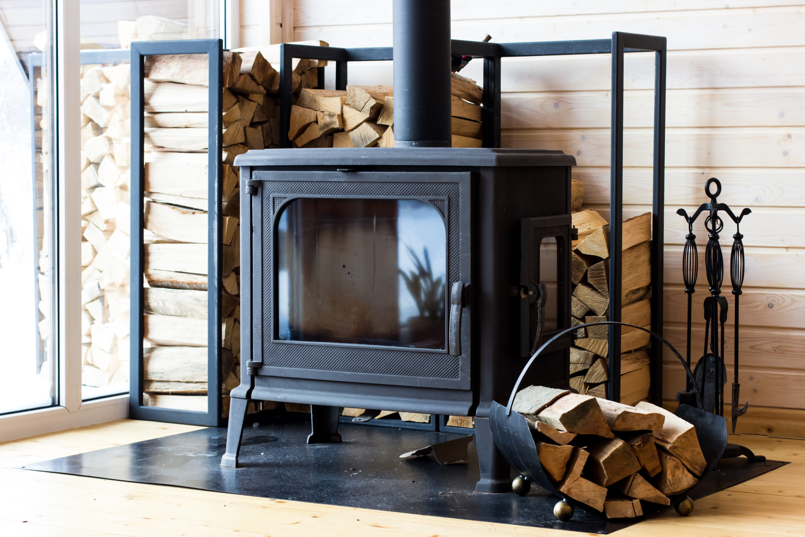 Installation de poêle à bois – Jérôme Dépannage Poêle à bois installé dans un intérieur chaleureux avec réserve de bois